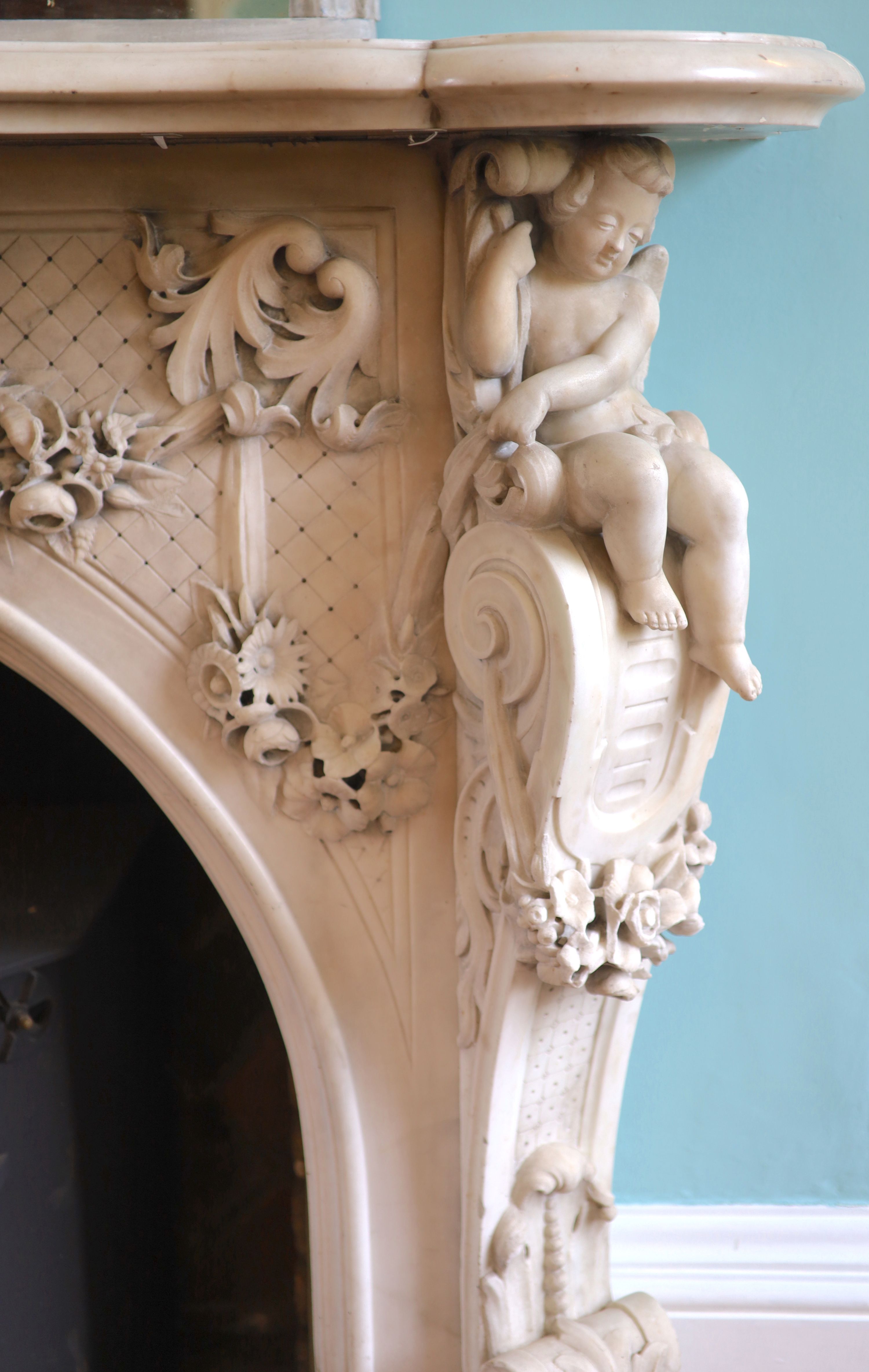 An important mid 19th century Italian white Carrara marble chimney piece, carved in the rococo taste, with seated putti, foliage swags